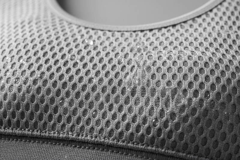 Macro close-up of breathable moisture-wicking sports bra fabric, visible weave texture, airflow concept, clean neutral background, professional textile photography